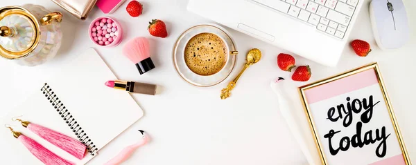 Female home workplace. Home office desk with laptop, notebook, fresh strawberries, cosmetics, women's accessories and coffee cup on white background. long web format for banner. Flat lay, top view