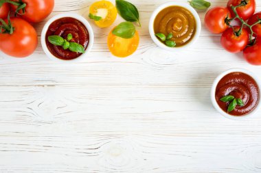Bir kase fesleğen ve beyaz ahşap masa üzerinde domates Domates ketçap sosu. Ketçap farklı türde. Üstten görünüm. Kopya alanı