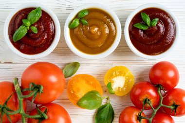 Bir kase fesleğen ve beyaz ahşap masa üzerinde domates Domates ketçap sosu. Ketçap farklı türde. Üstten görünüm