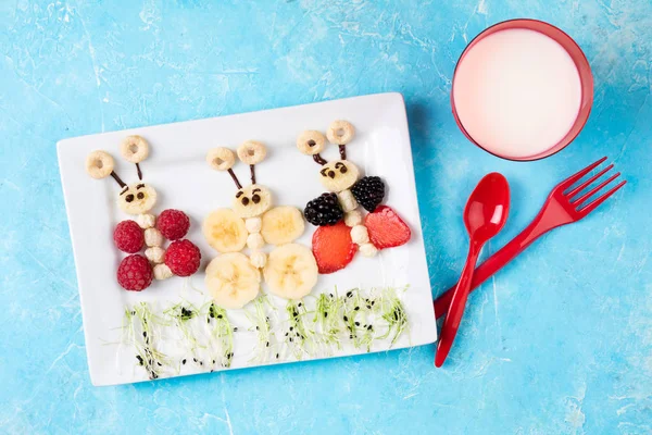Sandwiches and milk for kids breakfast. Funny butterfly sandwiches with berry, banana, chocolate, microgreen. Healthy children\'s eating. Top view