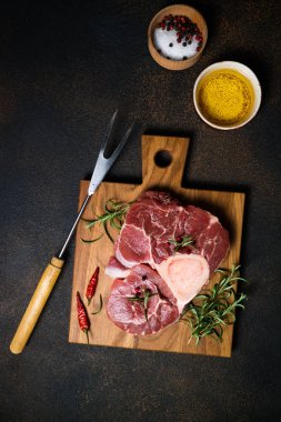 Ham taze Dana biftek osso bucco otlar ve baharatlar koyu arka plan üzerinde. Mermer et. Üstten görünüm kopya alanı