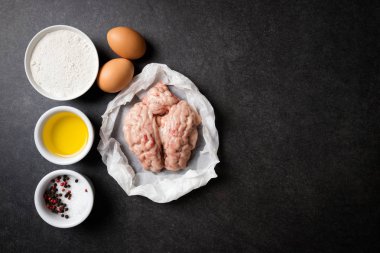 Ham beyin ve taş karanlık bir tablo üzerinde kızarmış beyin yemek pişirmek için malzemeler. Dana veya sığır beyni. Gurme yiyecekler. Üstten görünüm, kopya alanı