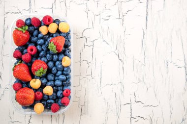 Taze yaban mersini, çilek ve ahududu ışık arka plan üzerinde. Ahşap masa üzerinde yaz meyveleri. Sağlıklı beslenme diyet gıda ve beslenme için kavram. Kopya alanı