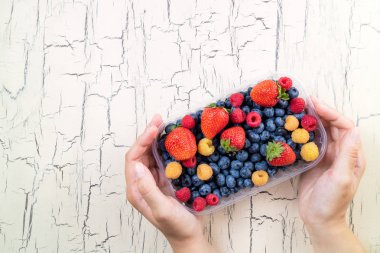 Taze tutan eller çilek yaban mersini, çilek ve ahududu ahşap arka plan üzerinde. Ahşap masa üzerinde yaz meyveleri. Kavramı için sağlıklı beslenme, diyet gıda ve beslenme