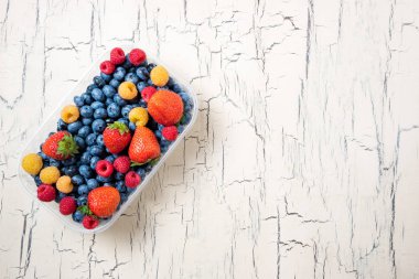 Taze yaban mersini, çilek ve ahududu ışık arka plan üzerinde. Ahşap zemin üzerine yaz meyveleri. Sağlıklı gıda diyet kavramı. Kopya alanı