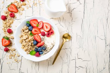 Granola çilek ve yoğurt ile kahvaltıda. Mısır gevreği yulaf ezmesi veya müsli çilek, yaban mersini ve ahududu. Kavram diyet, sağlıklı yiyecek ve yemek. Üstten Görünüm, kopya alanı