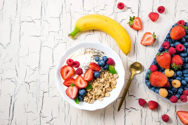 Granola çilek, yoğurt ve meyve ile kahvaltıda. Çilek, yaban mersini ve ahududu tahıl yulaf ezmesi. Meyve ve çilek ile müsli. Kavram diyet, sağlıklı yiyecek ve yemek. Üstten Görünüm