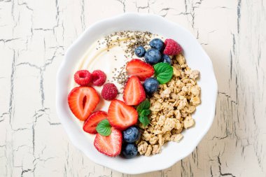 Granola çilek ve yoğurt ile kahvaltıda. Mısır gevreği yulaf ezmesi veya müsli çilek, yaban mersini ve ahududu. Kavram diyet, sağlıklı yiyecek ve yemek. Üstten Görünüm