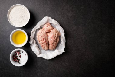 Ham beyin ve kızarmış beyin taş karanlık masada yemek pişirmek için malzemeler. Dana veya sığır beyni. Gurme yiyecekler. En iyi görünüm ve kopya alanı