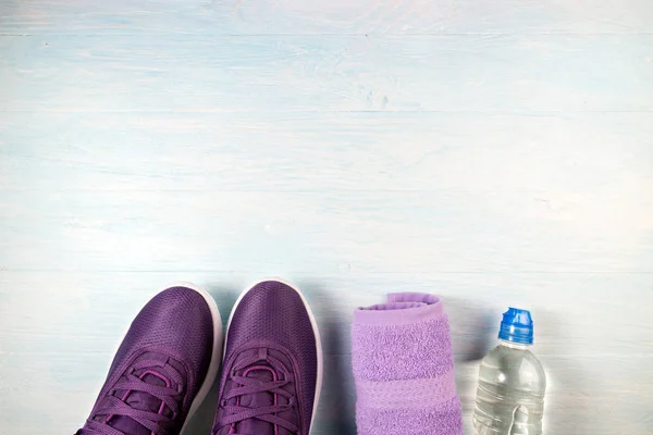 Sport shoes, bottle of water and towel on blue wooden background — Stock Photo, Image