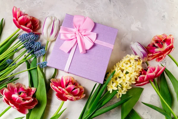 Fond festif avec des fleurs et boîte cadeau. Tulipes, fleurs printanières et présents. Carte de voeux, vacances, Pâques, concept de fête des mères. Pose plate — Photo