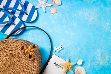 Yaz kadın moda plaj aksesuarları flip flop, bambu çanta ve pasaport mavi arka plan üzerinde. Yolculuk, meslekler, seyahat ve yaz dinlenme konsepti. Üstte görüntü