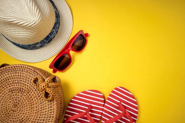Літні жіночі модні пляжні аксесуари фліп-флоп, солом'яний капелюх, сонцезахисні окуляри на жовтому тлі. Подорож, покликання, подорожі та літній відпочинок — стокове фото