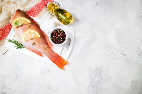 Fisk rå snapper med citronskivor, örter rosmarin, salt och peppar på vit bakgrund. Hälsosam mat och bantning koncept. Ingredienser för tillagning av fisk — Stockfoto