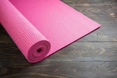 Ahşap arka plan üzerinde pembe yoga paspas. Yoga için ekipman. Kavram 