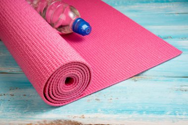 Pembe yoga mat ve mavi ahşap arka plan üzerinde su şişesi. Equ