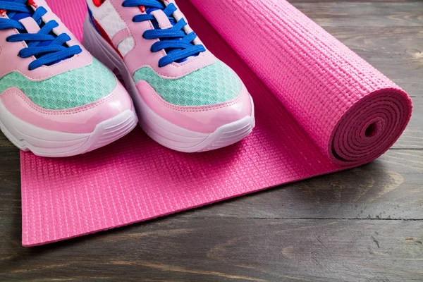 Tapete de ioga rosa e sapatos esportivos em fundo de madeira. Vida saudável — Fotografia de Stock