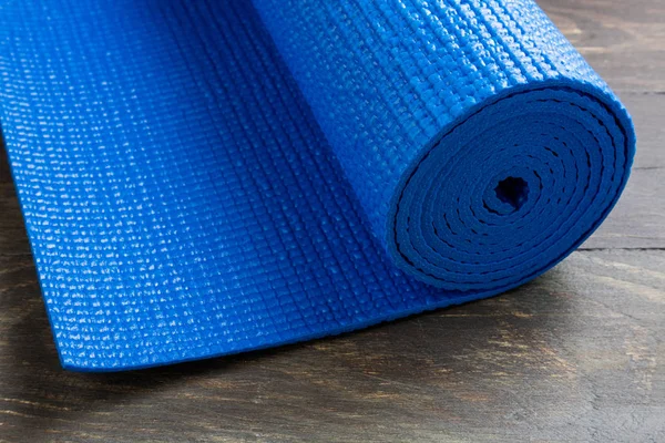 Blue yoga mat on wooden background. Equipment for yoga. Concept
