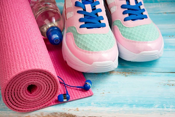 Tapete de ioga rosa, sapatos esportivos, garrafa de água e fones de ouvido em blu — Fotografia de Stock