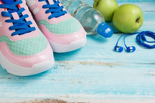 Sapatos esportivos, garrafa de água, maçãs e fones de ouvido em azul backg — Fotografia de Stock