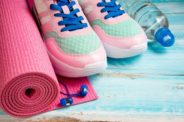 Tapete de ioga rosa, sapatos esportivos, garrafa de água e fones de ouvido em blu — Fotografia de Stock