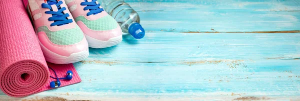 Pink yoga mat, sport shoes, bottle of water and earphones on woo — Stock Photo, Image