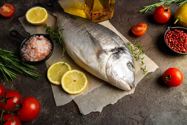 Dorado de peixe cru com limão, ervas, especiarias e tomate em bac escuro — Fotografia de Stock