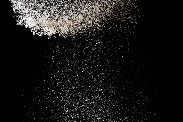 Mjöl siktning på en svart bakgrund. Vitt pulver stänk isolat — Stockfoto