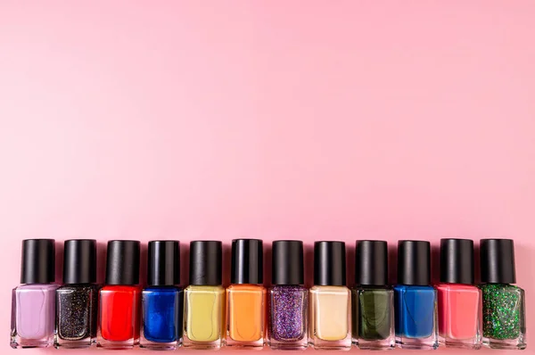 Set of various nail polish bottle on pink background with copy s