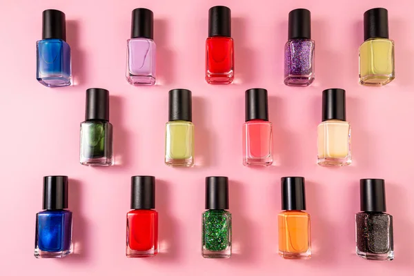 Pattern of various nail polish bottle on pink background. Stylis