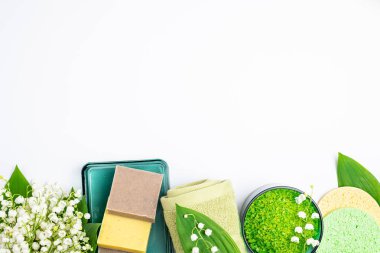 Spa tedavisi sağlık konsepti. Doğal kaplıca ürünleri, havlular, aksesuarlar, banyo süngeri, sabun, bitkisel deniz tuzu, beyaz arka planda çiçekler. Spa arka planı. Boşluğu kopyala