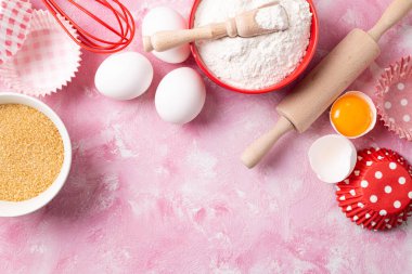 Pişirme arka planı. Yemek malzemelerinin çerçevesi un, yumurta, pembe düzlükte şeker. Pişirme, kek pişirme ya da kek pişirme. Üst görünüm, alanı kopyala