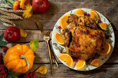 Şükran Günü geçmişi. Ahşap masada Şükran Günü kutlamaları için turunçgil ve baharatlı fırında tavuk veya hindi. Şükran Günü yemeği için sonbahar sofrası hazırlıkları. Üst görünüm