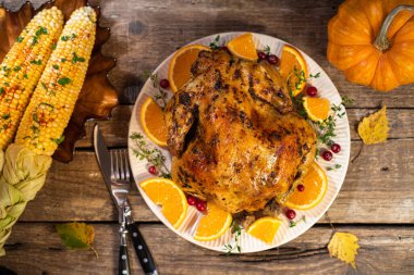 Şükran Günü geçmişi. Ahşap masada Şükran Günü yemeği için turunçgil ve baharatlı fırında tavuk ya da hindi. Şükran Günü için sonbahar masası ayarları. Üst görünüm