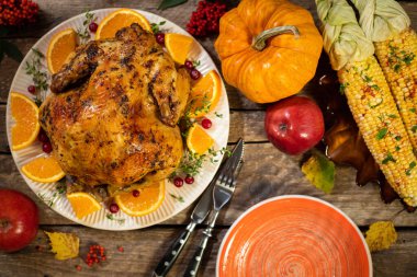 Şükran Günü sonbahar kompozisyonları. Kızarmış tavuk ya da turunçgil ve baharatlı hindi. Tahta masada şükran günü için mısır. Şükran Günü yemeği için şenlik masası ayarları. Üst görünüm