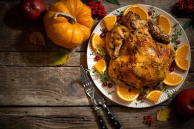 Şükran Günü sonbahar kompozisyonları. Tahta masadaki Şükran Günü kutlamaları için kızarmış tavuk ya da turunçgil ve baharatlı hindi. Şükran Günü yemeği için şenlik masası ayarları. Üst görünüm