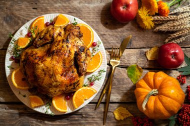 Şükran Günü için fırında tavuk. Tahta masadaki Şükran Günü kutlamaları için kızarmış tavuk ya da turunçgil ve baharatlı hindi. Şükran Günü yemeği için şenlik masası ayarları. Üst görünüm