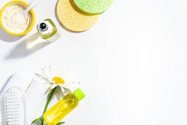 Spa aksesuarları kil yüz maskesi, sünger, papatya çiçeği özlü yüz losyonu, havlular, beyaz arka planda gerekli yağ, üst manzara. Kadınlar doğal malzemelerle makyaj yaparlar.