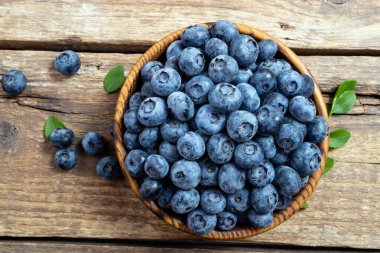Tahta kasede taze yaban mersini. Kırsal masada yeşil yapraklı sulu ve taze yaban mersini. Sağlıklı beslenme ve yeme için yabanmersinli antioksidan kavramı. Üst görünüm