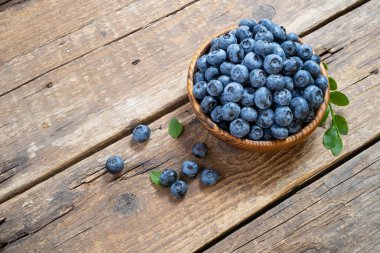 Tahta kasede taze yaban mersini. Kırsal masada yeşil yapraklı sulu ve taze yaban mersini. Sağlıklı beslenme ve yeme için yabanmersinli antioksidan kavramı. Üst görünüm, alanı kopyala