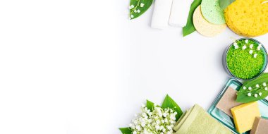 Spa tedavisi sağlık konsepti. Spa arka planı düzleştirilmiş. Doğal kaplıca ürünleri, havlular, aksesuarlar, banyo süngeri, sabun, bitkisel deniz tuzu, beyaz arka planda çiçekler. Uzayı uzun biçimde kopyala