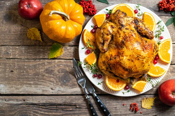 stock image Thanksgiving background. Baked chicken or turkey with citrus and spices for celebrations for Thanksgiving Day on wooden table. Autumn table settings for Thanksgiving dinner. Top view