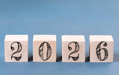 2026 mutlu yıllar. 2026 numaralı tahta blok mavi üzerine. 2026 'nın yeni yıl geçmişi. İş, kararlar, hedefler, ilham, başarı, fikirler