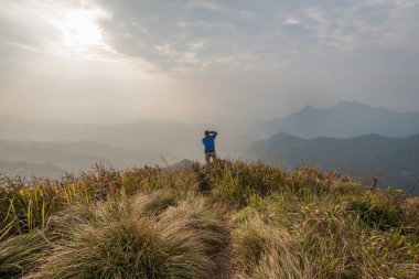 Chiang Rai, Tayland 'da Phu Chi Fa' nın tepesinde fotoğraf çeken bir adam görülüyor..