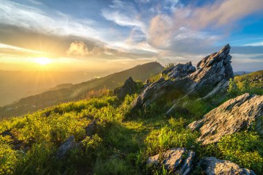 Doi Pha Tang 'ın altın gün batımının manzarası Chiang Rai' de kayalık ön planda..