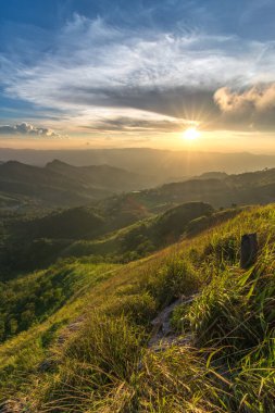 Doi Pha Tang 'ın üzerinde gün batımının güzel manzarası. Chiang Rai, Tayland' da yeşil çimen ön planda..