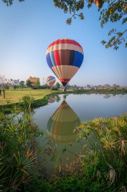 Tayland 'ın Chiang Rai kentindeki göletin üzerindeki sıcak hava balonunun güzel bir yansıması..