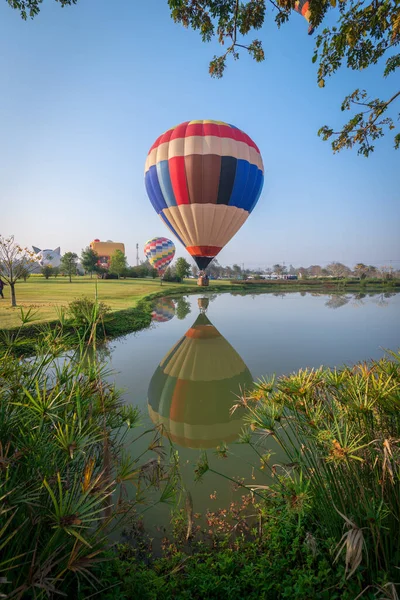Tayland 'ın Chiang Rai kentindeki göletin üzerindeki sıcak hava balonunun güzel bir yansıması..
