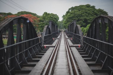 Kanchanaburi, Tayland 'da Kwai Nehri üzerinde tek başına yürüyen bir adamın manzarası..