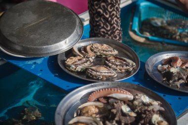 Taze deniz kabukları, deniz kulağı ve Haenyeo (kadın dalgıçlar; UNESCO Soyut Kültür Mirasları Listesi, 2016) tarafından Güney Kore Jeju Adası 'nda toplanan diğer taze deniz ürünleri.